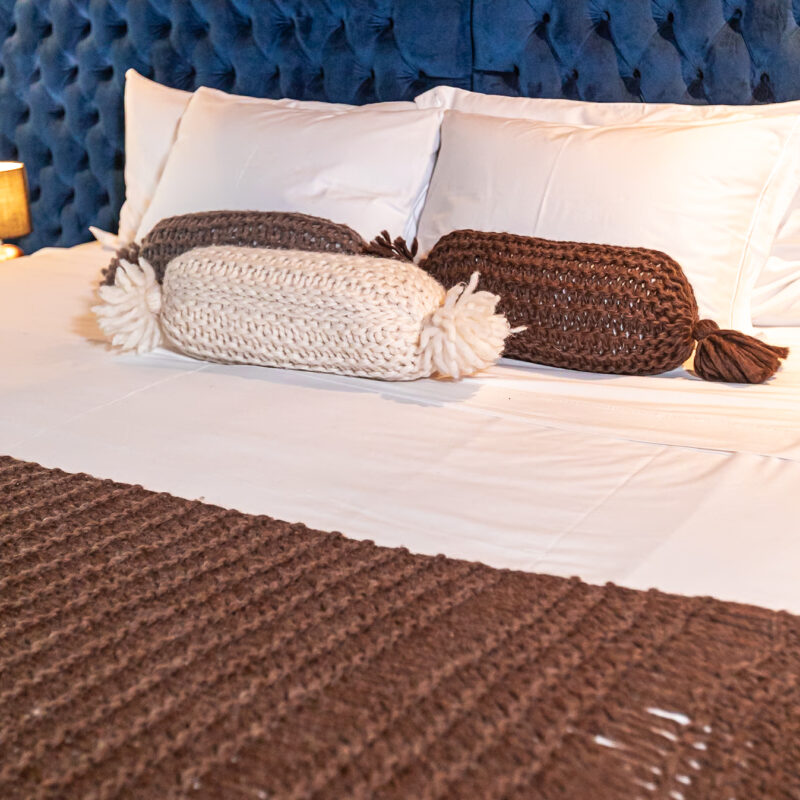 almofada cilíndrica de lã natural feita à mão em tricô artesanal pelas artesãs das Mãostiqueiras