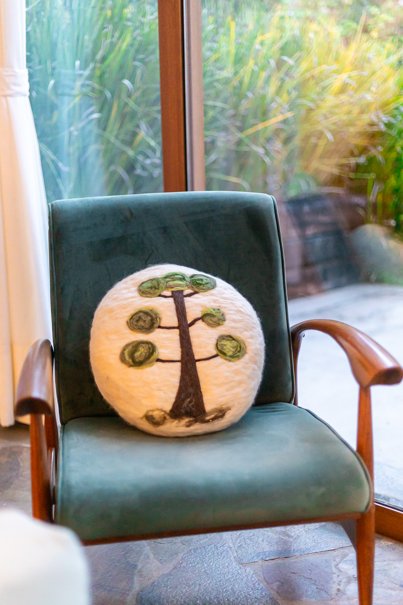 almofada artesanal redonda de feltragem com desenho de araucária feita em lã natural cardada nas cores naturais da lã